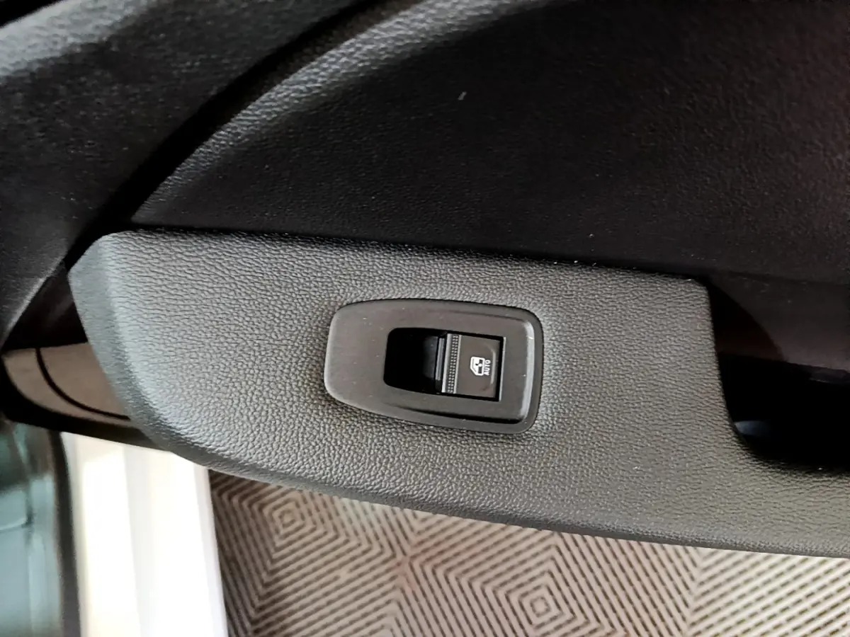 Gros plan sur le bouton de verrouillage électrique de la porte côté conducteur d'une Renault Clio Business blanche.