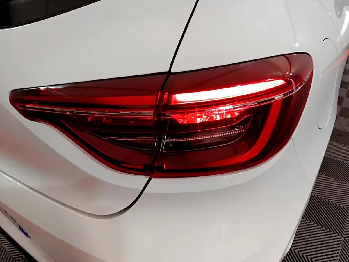 Feu arrière droit allumé d'une Renault Clio Business TCe 90 blanche, vue rapprochée sur la carrosserie arrière.