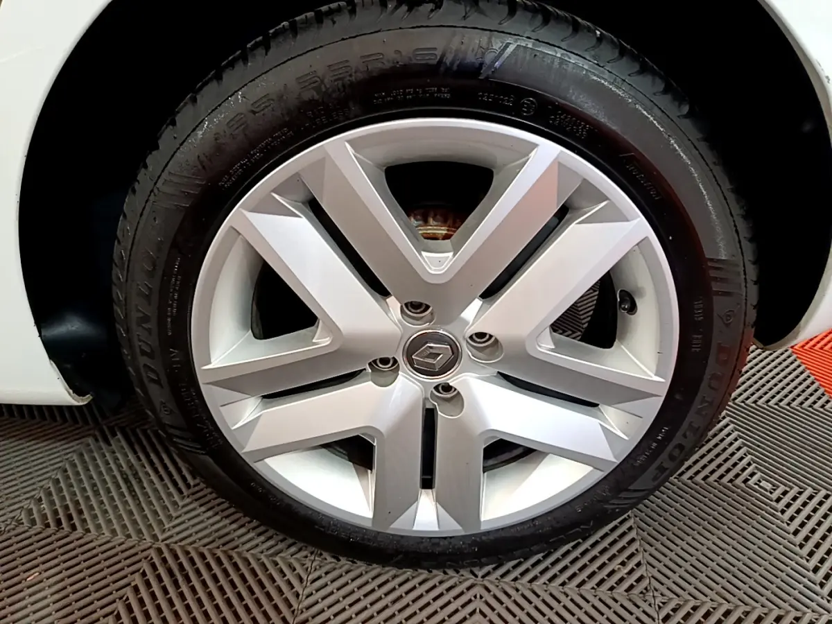 Vue rapprochée sur la roue avant gauche d'une Renault Clio blanche, mettant en valeur le pneu Dunlop et l'aile du véhicule.