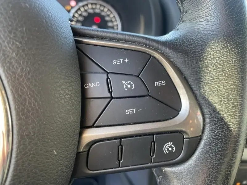 Gros plan sur les commandes de régulateur de vitesse au volant en cuir noir du Jeep Renegade blanc 2019.