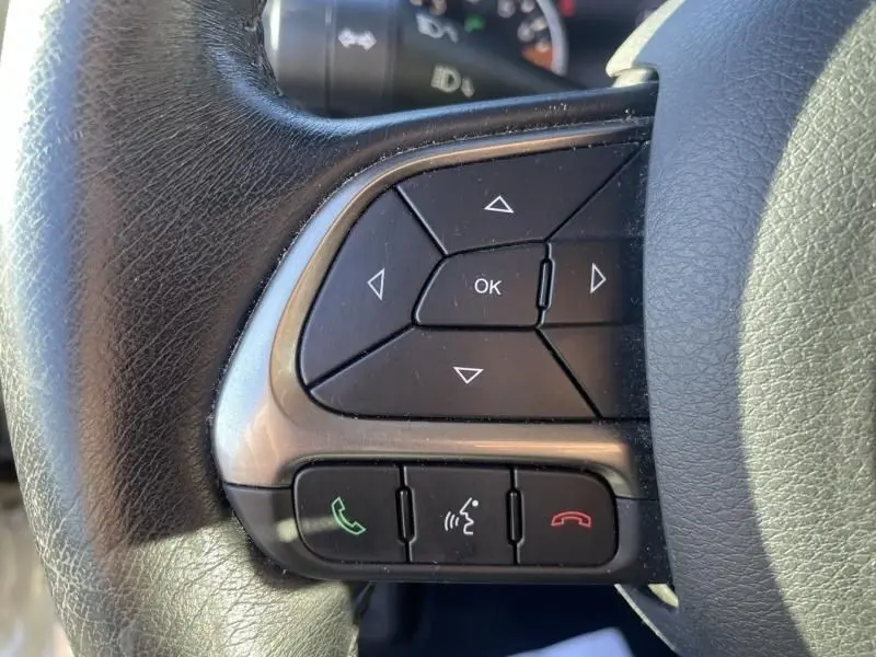 Gros plan sur les commandes multifonctions noires du volant en cuir d’un Jeep Renegade blanc, version Limited 2019.