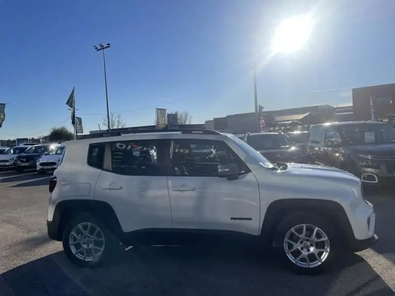Jeep Renegade blanc vue de profil côté gauche, avec jantes alliage et toit noir contrastant, en extérieur lumineux.
