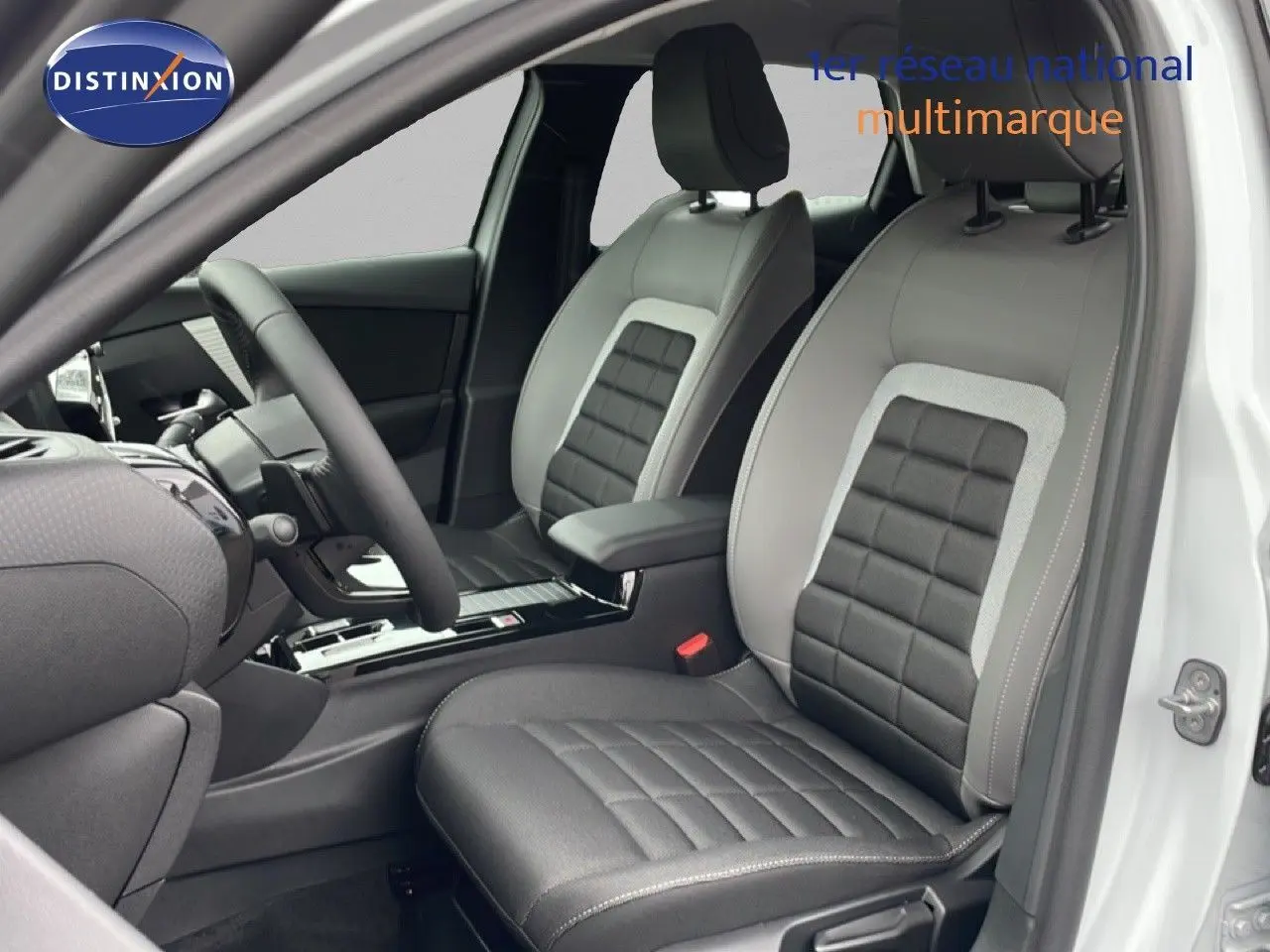 Vue intérieure côté conducteur d'une Citroën C4 blanc métal, sièges en cuir et tissu noir avec surpiqûres grises.