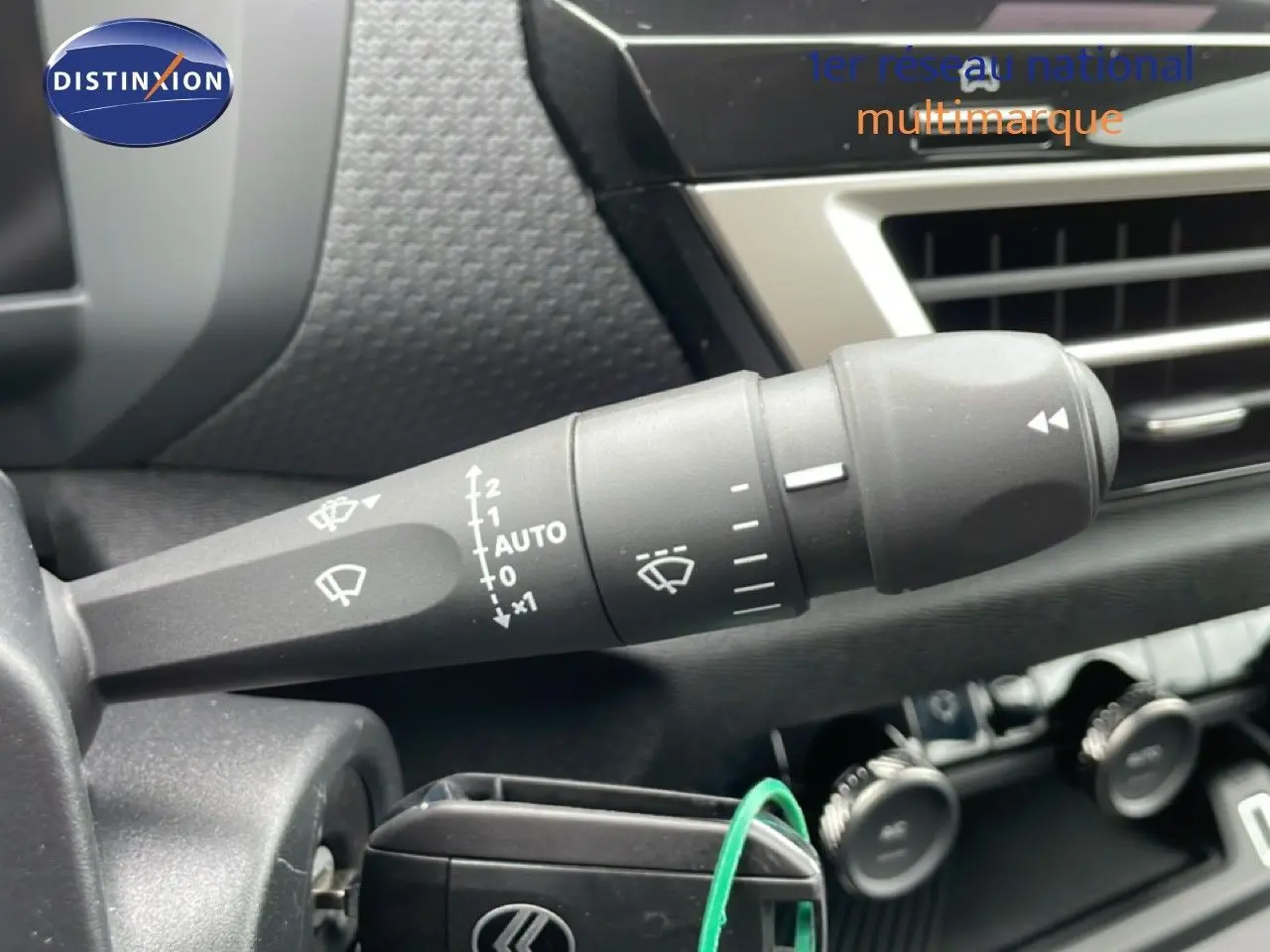 Gros plan sur la commande d’essuie-glace à droite du volant dans l’habitacle noir d’une Citroën C4 blanc métal.
