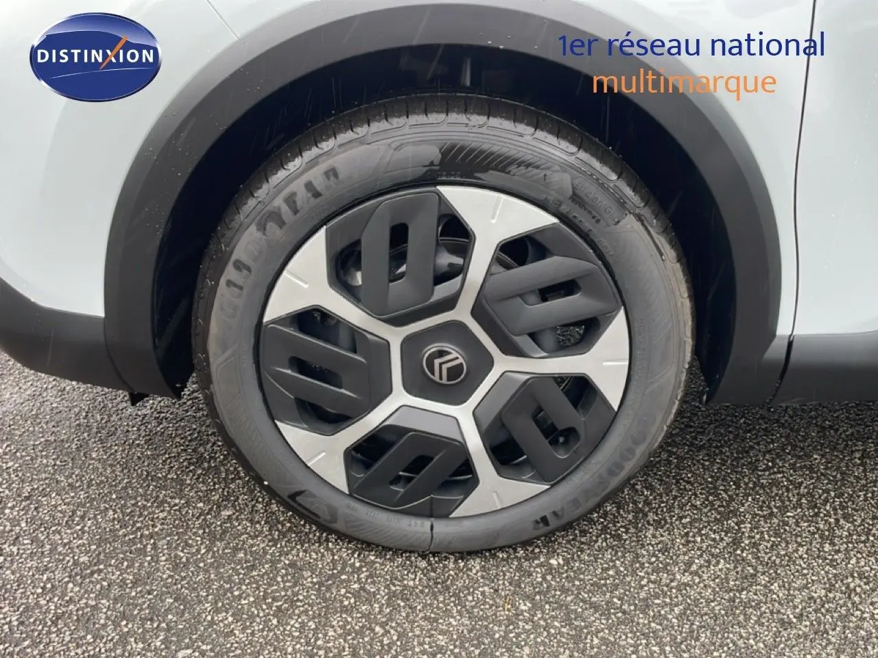 Gros plan sur la roue avant gauche d'une Citroën C4 blanc métal, mettant en valeur la jante au design moderne bicolore.