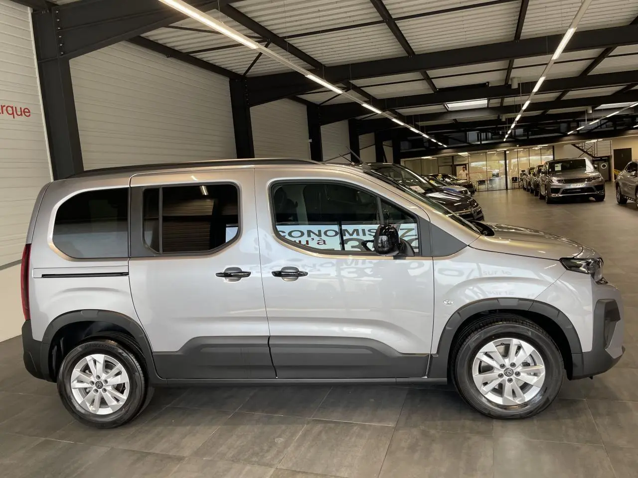 Peugeot Rifter gris Artense vu de profil côté gauche, avec portes coulissantes et jantes tôles 16 pouces.