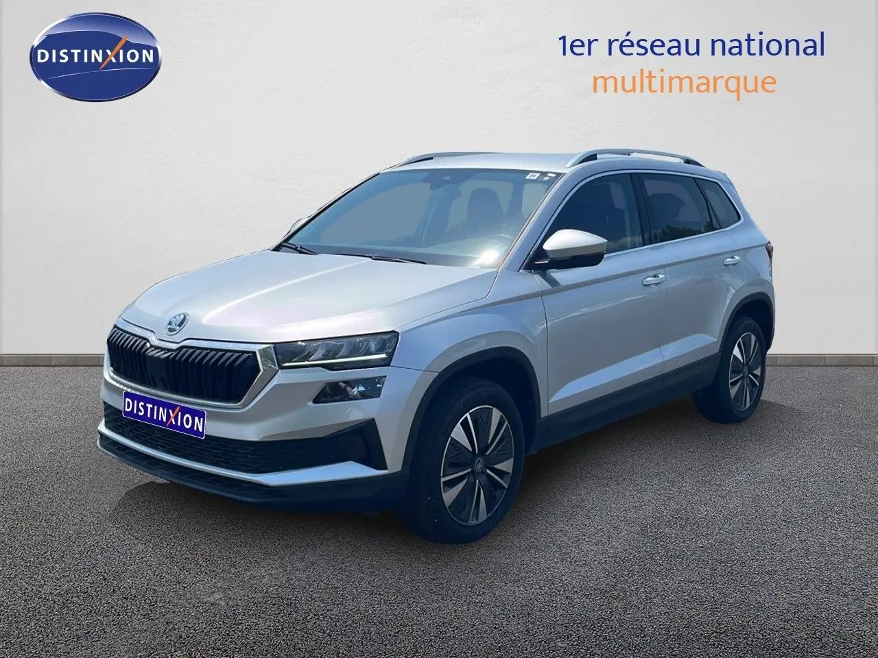 Vue 3/4 avant d’un Skoda Karoq 2025 gris argenté avec jantes bi-ton et calandre noire distinctive.