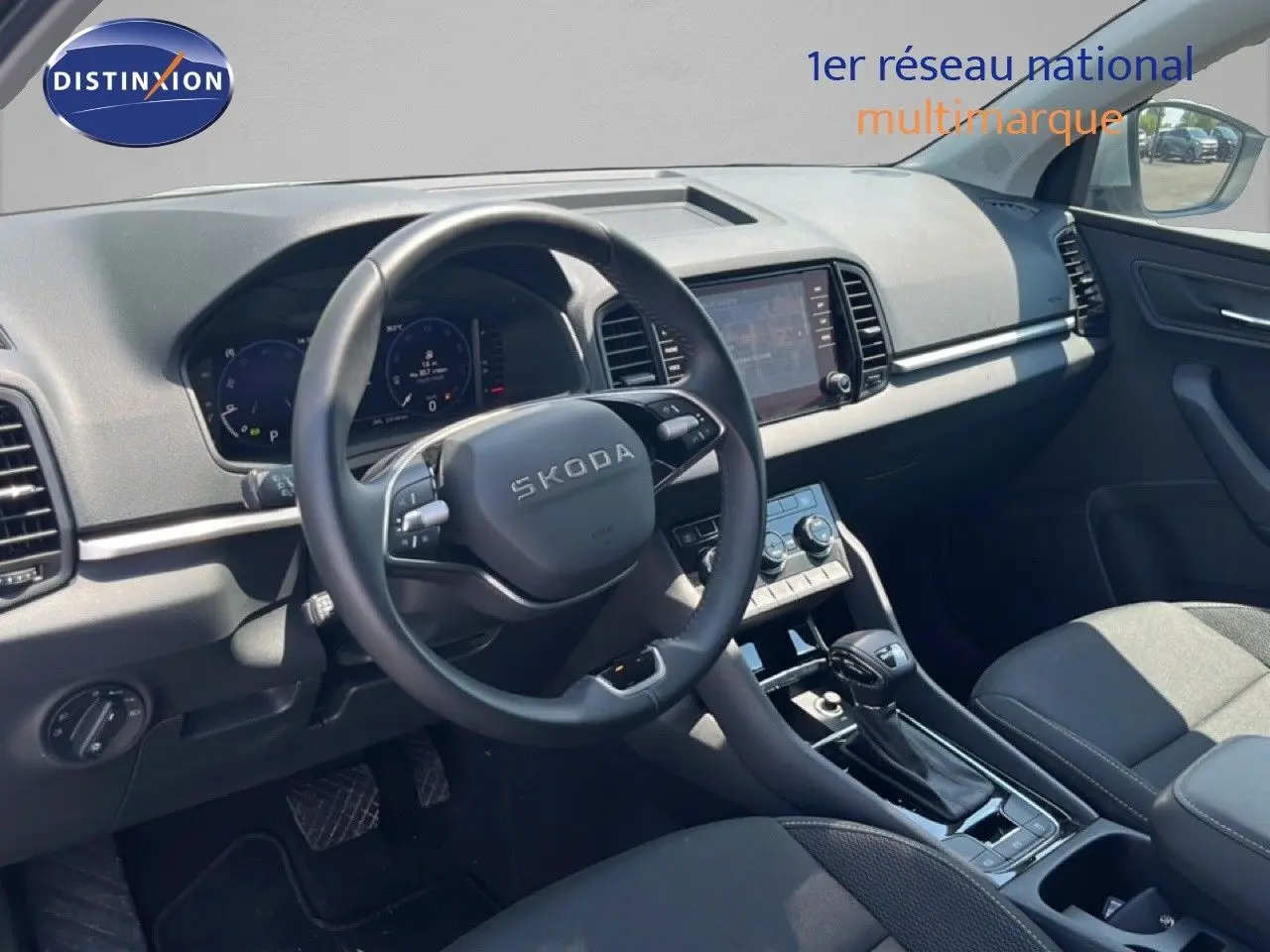 Vue intérieure côté conducteur du Skoda Karoq 2025, tableau de bord et volant noirs avec écran tactile central.