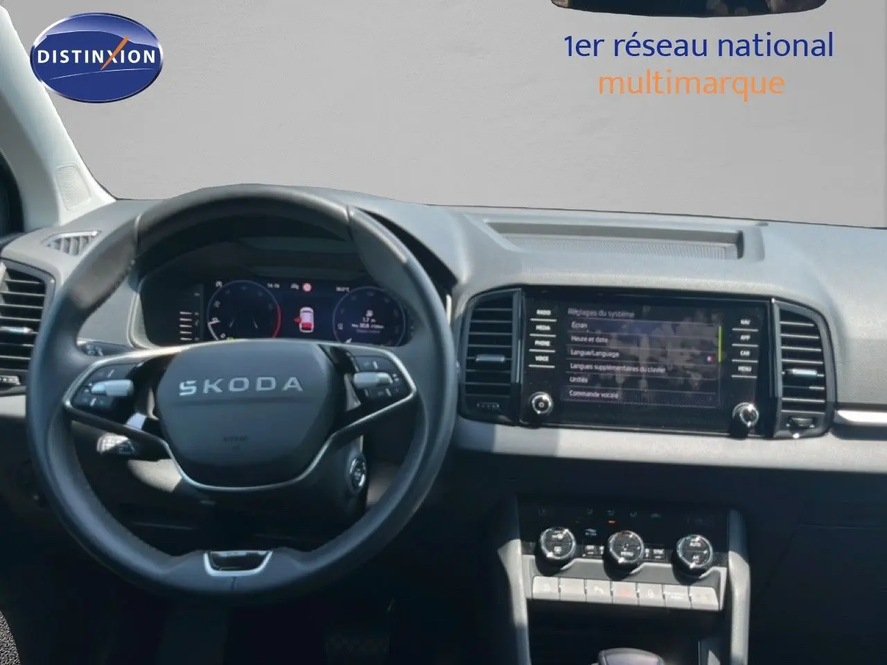 Vue intérieure centrée sur le volant SKODA et le tableau de bord avec écran tactile et commandes climatisation.