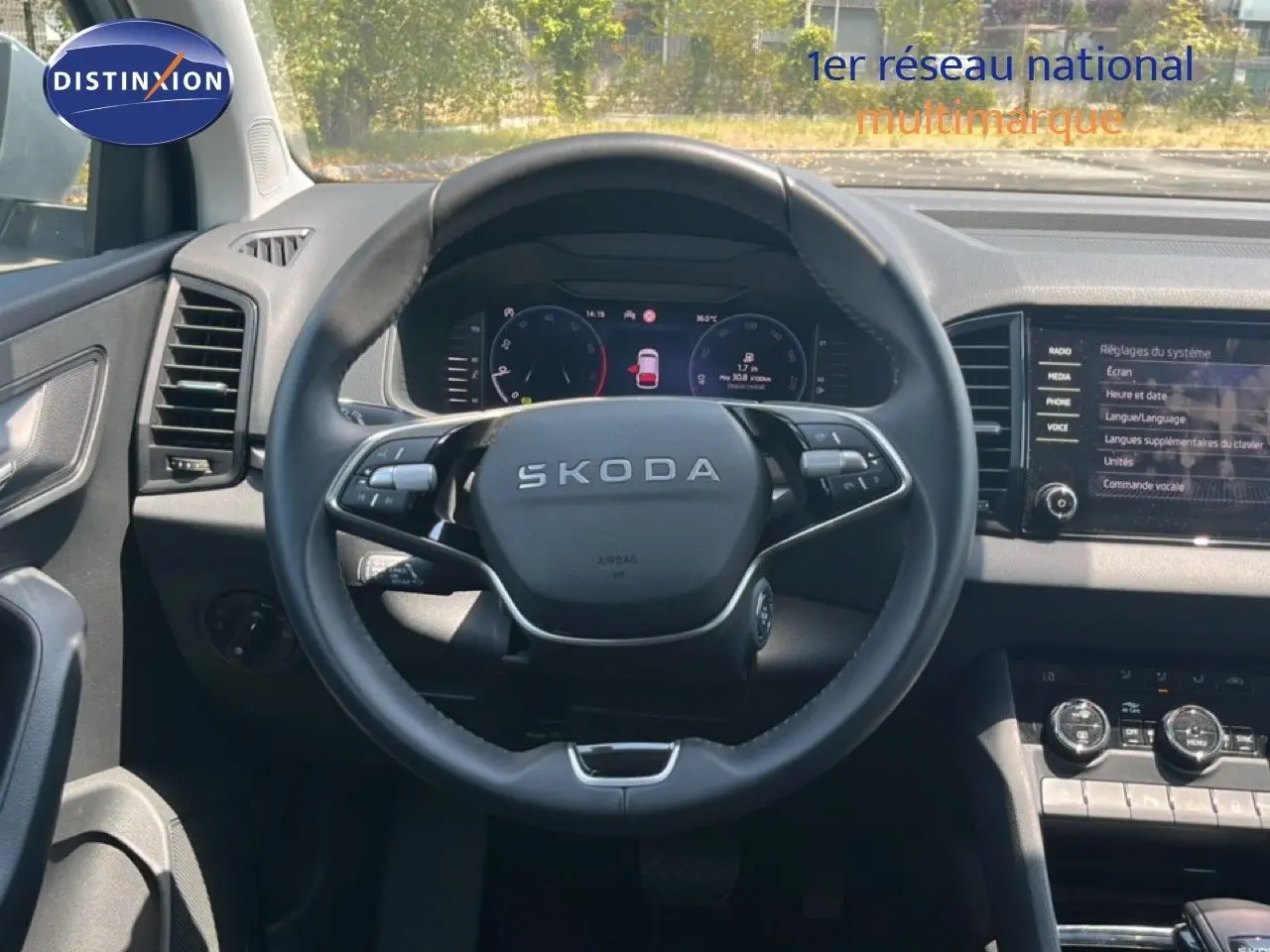 Vue intérieure centrée sur le volant SKODA d’un Karoq 2025, avec tableau de bord numérique et écran tactile gris noir.