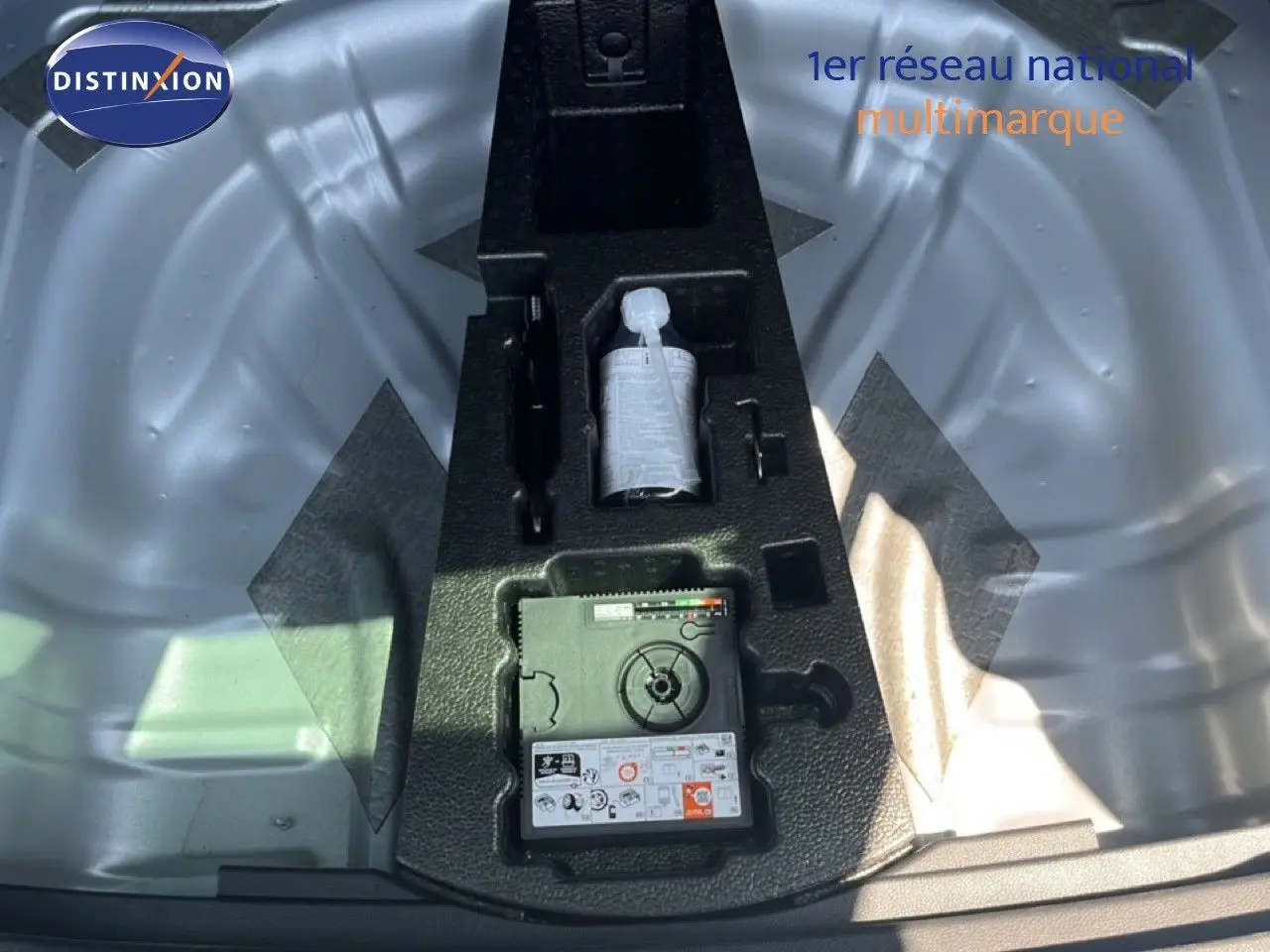 Vue plongeante sur le coffre ouvert d'un Skoda Karoq 2025 en argent, montrant le kit de réparation pneus intégré.
