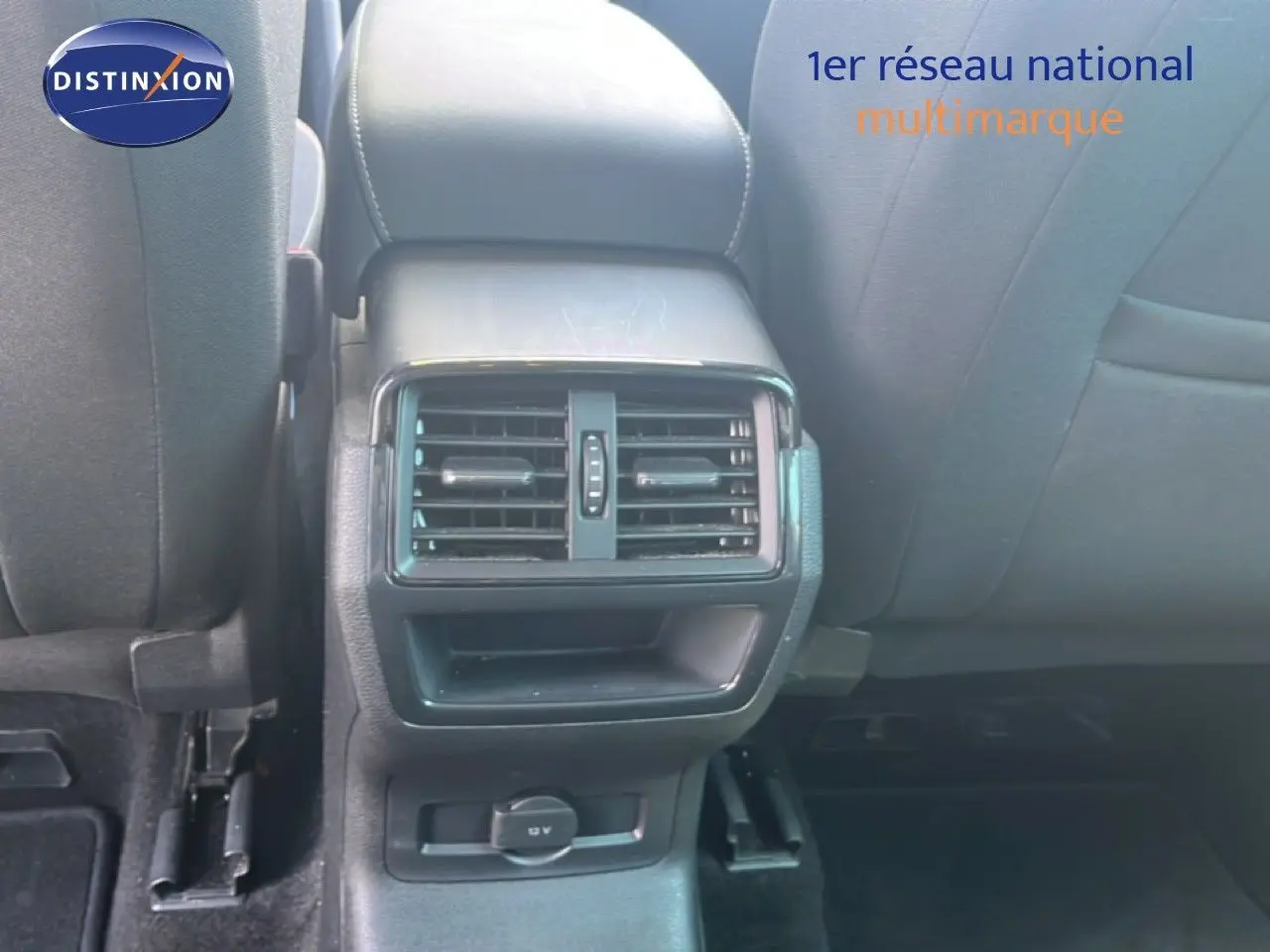 Vue rapprochée des aérateurs arrière et prise 12V sur la console centrale d’un Skoda Karoq gris intérieur tissu noir.