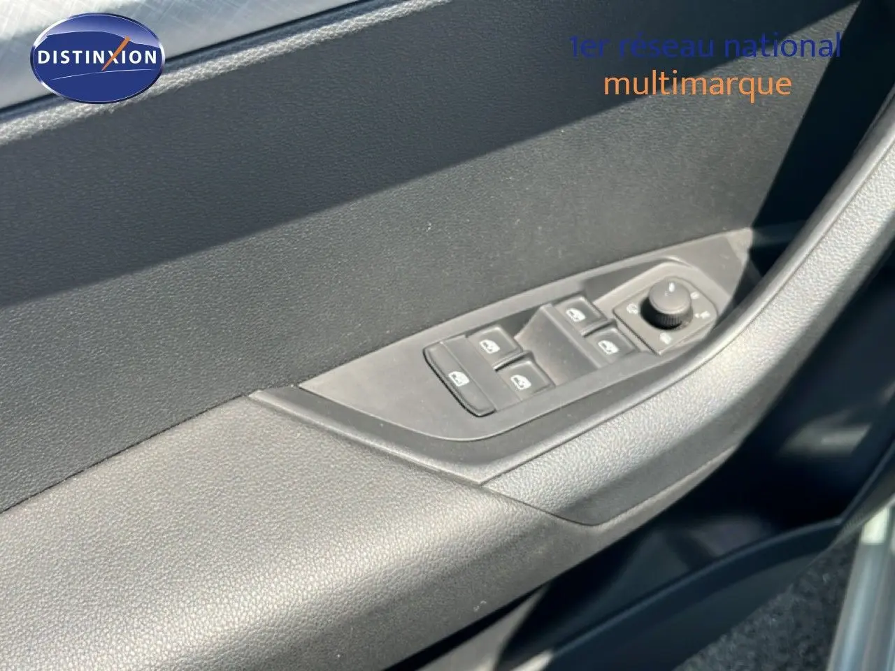 Gros plan sur la commande des vitres électriques côté gauche de la porte d’une Skoda Karoq 1.5 TSI 2025 couleur argent.