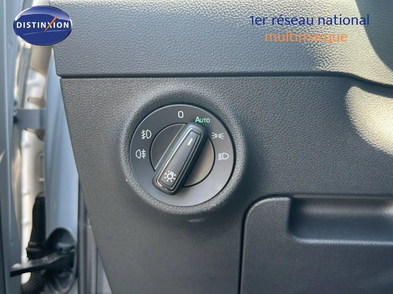 Gros plan sur la molette de commande des phares dans l'habitacle gris noir du Skoda Karoq Reflex Silver.