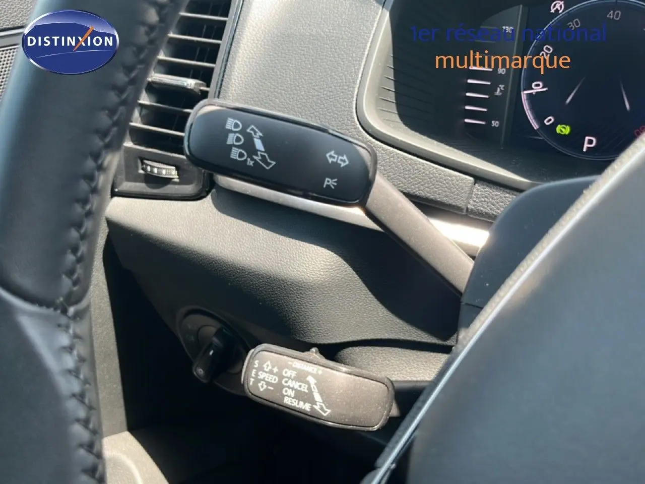 Gros plan sur la commande de régulateur de vitesse à gauche du volant dans un Skoda Karoq gris argenté.