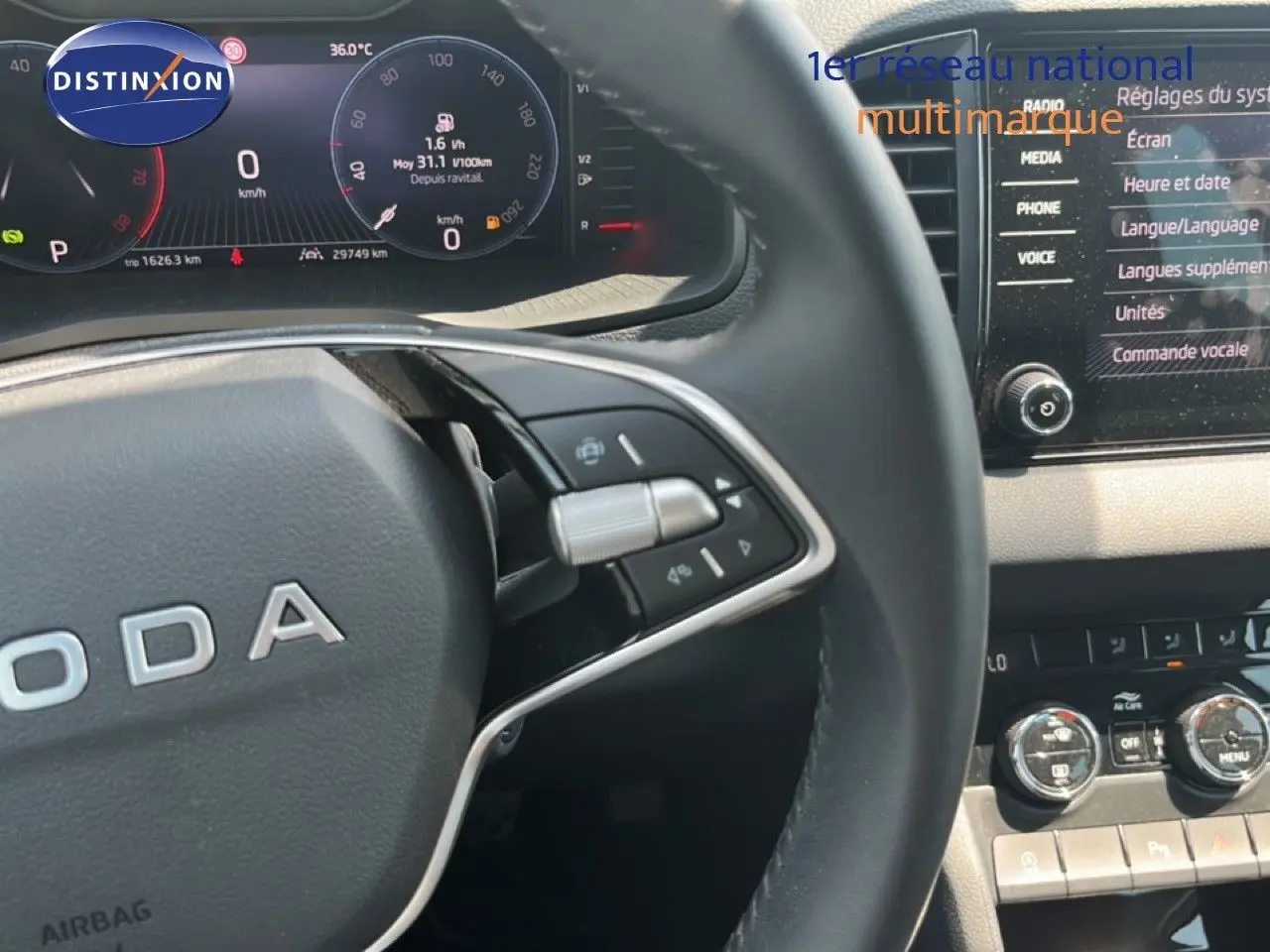 Gros plan sur le volant et le tableau de bord numérique d’un Skoda Karoq 2025, finition Selection, intérieur gris noir.