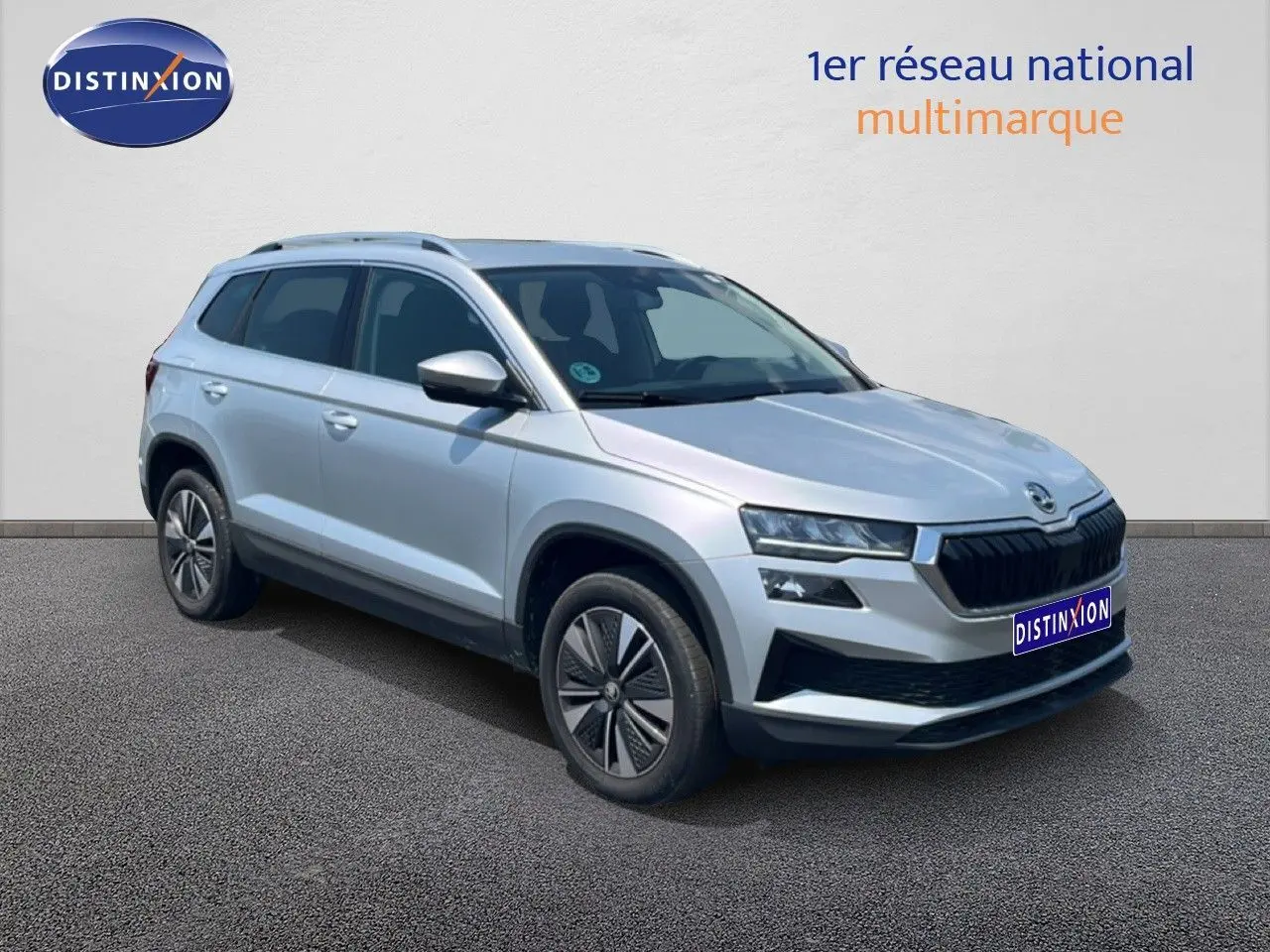 Vue 3/4 avant d’un Skoda Karoq 2025 en Reflex Silver Metal avec calandre noire et jantes bi-ton.