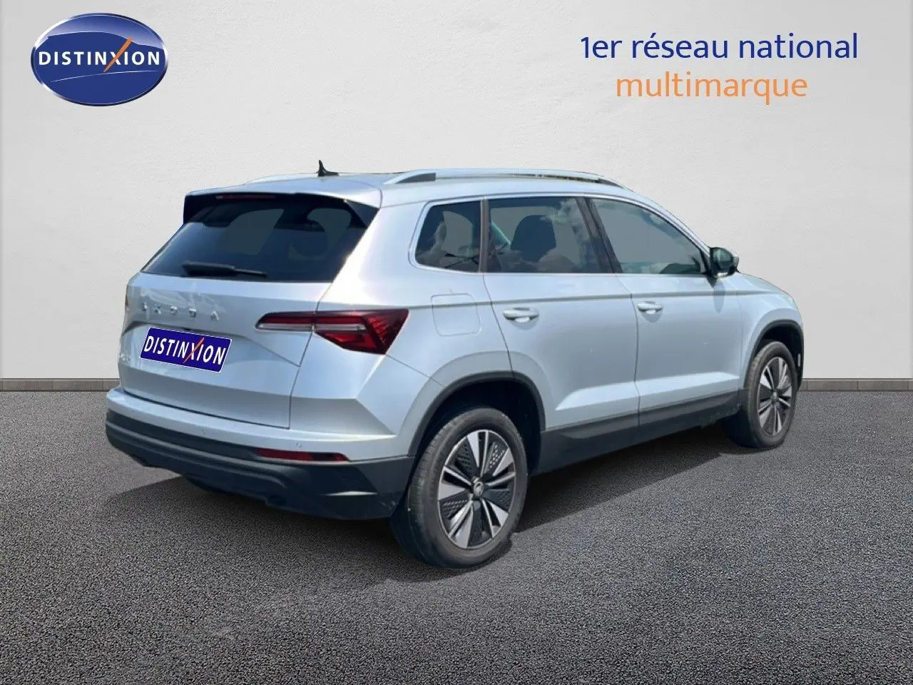 Vue 3/4 arrière droite d'un Skoda Karoq 2025 en Reflex Silver Metal avec jantes bi-ton et vitres teintées.