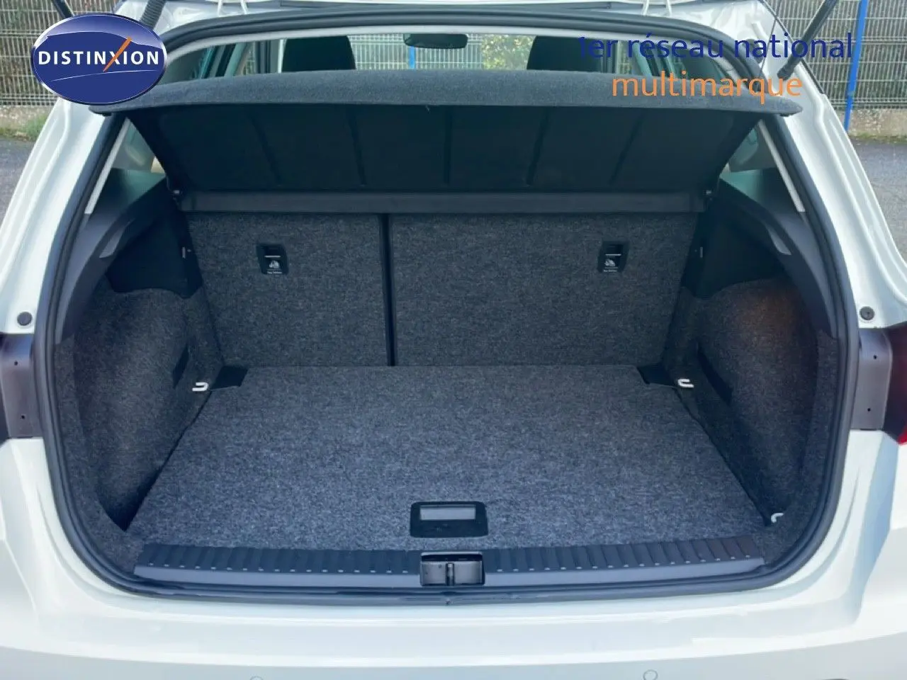 Coffre ouvert vu de l'arrière d'un SEAT Arona blanc avec toit gris, montrant l'espace de chargement vide et tapissé.