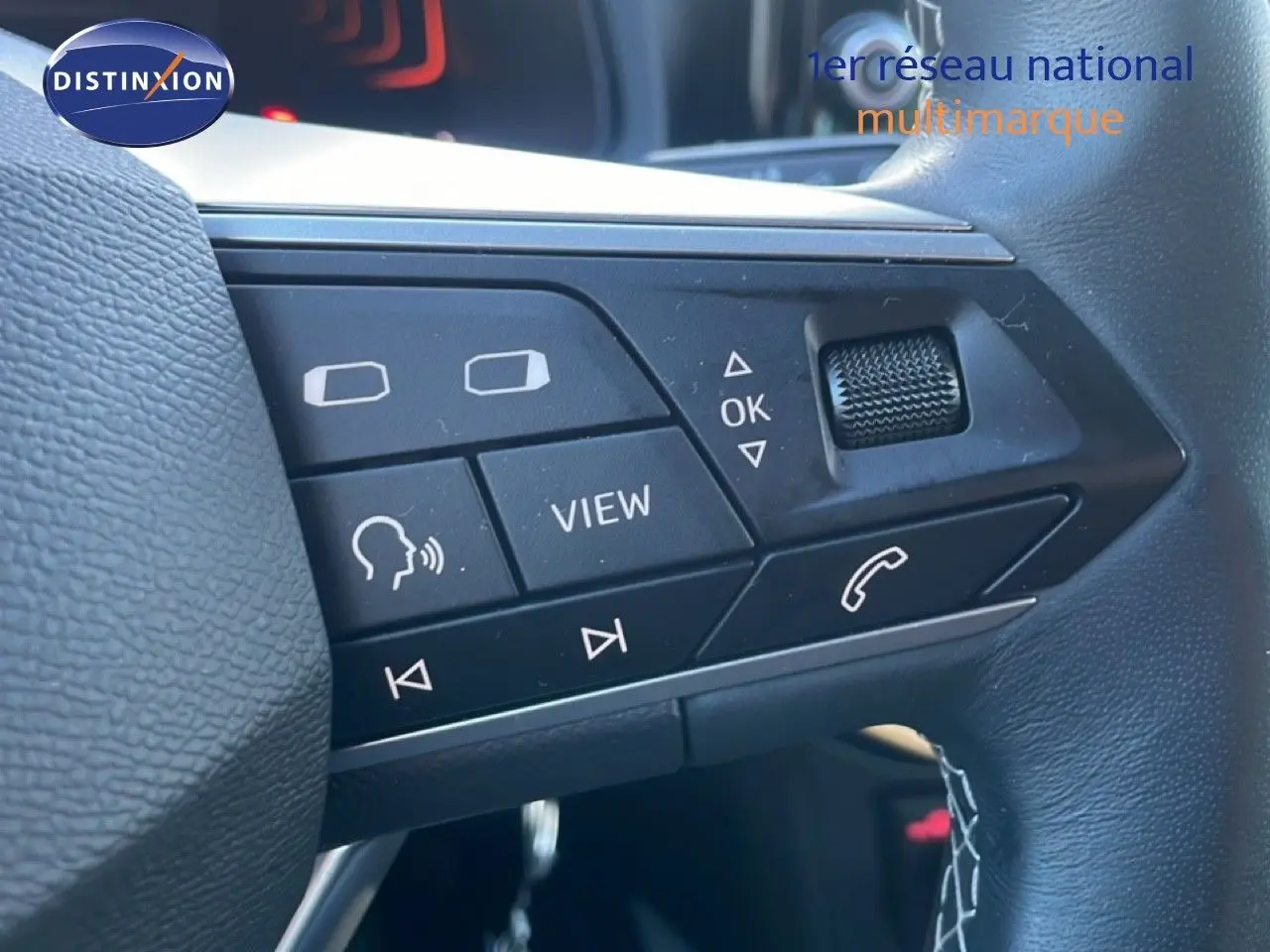 Gros plan sur les commandes multifonctions du volant en cuir noir d’un SEAT Arona blanc toit gris 2025.
