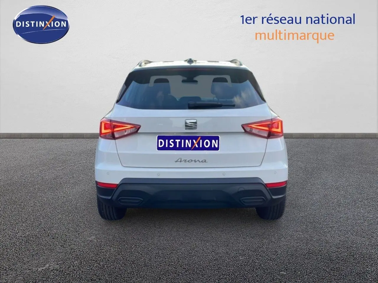 Vue arrière d'un SEAT Arona blanc avec toit gris, feux allumés, sur fond neutre.