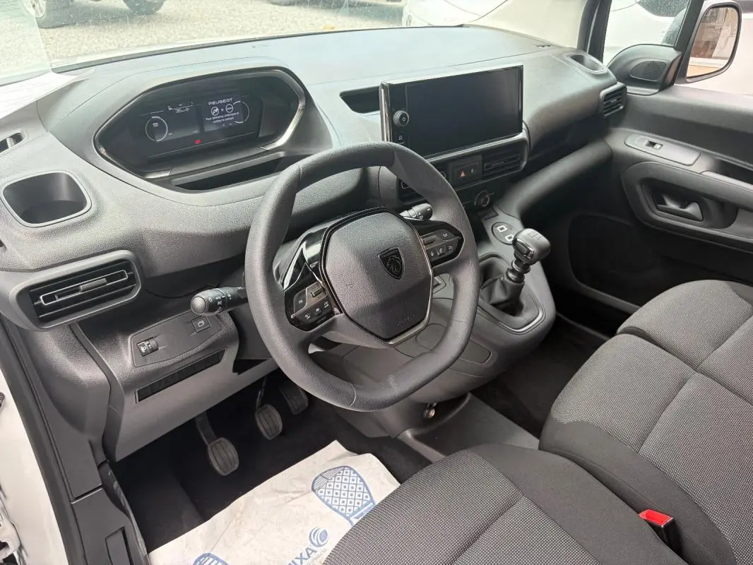 Vue intérieure côté conducteur du Peugeot Partner 2026, volant multifonctions, écran tactile et boîte manuelle visibles.