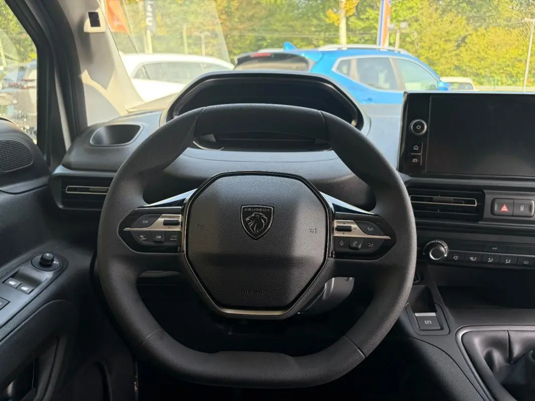 Vue intérieure centrée sur le volant cuir multifonctions du Peugeot Partner blanc, avec tableau de bord et écran tactile visibles.