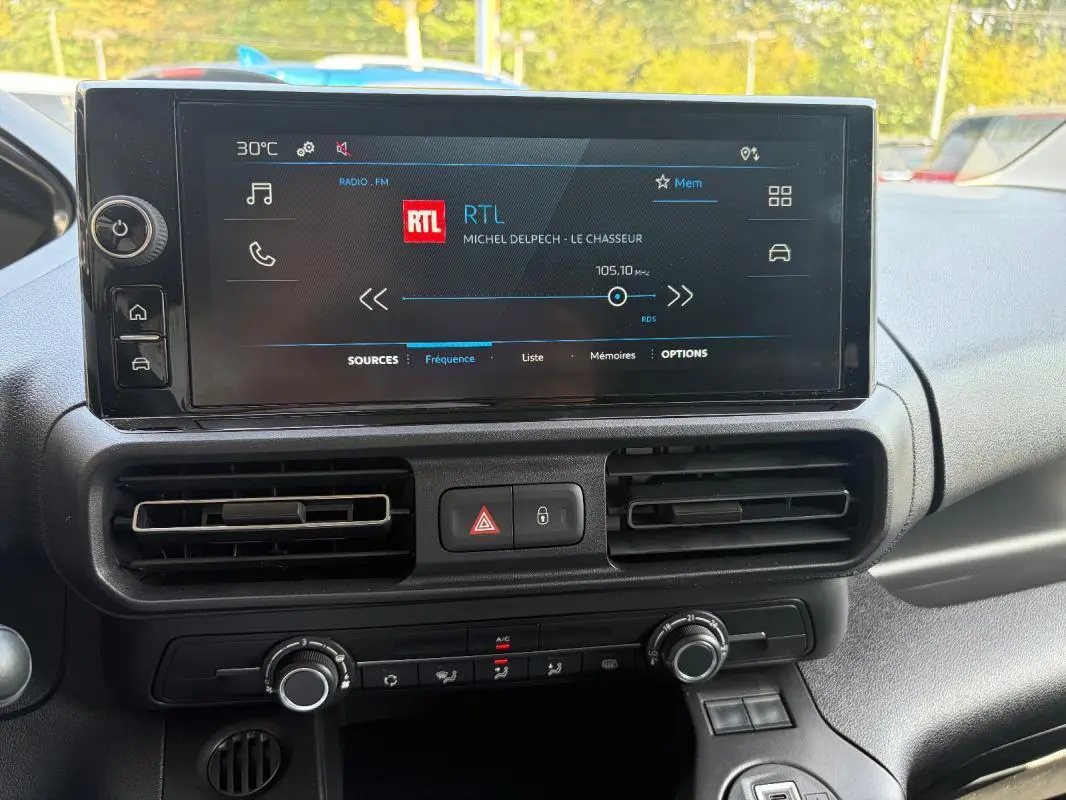 Écran tactile central du Peugeot Partner 2026 montrant la radio RTL, avec commandes climatisation et boutons de sécurité.