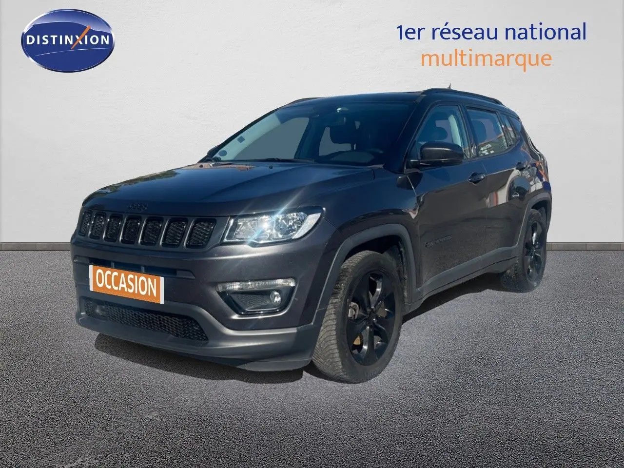 Jeep Compass gris foncé en 3/4 avant droit, version Brooklyn Edition avec jantes noires et calandre distinctive.