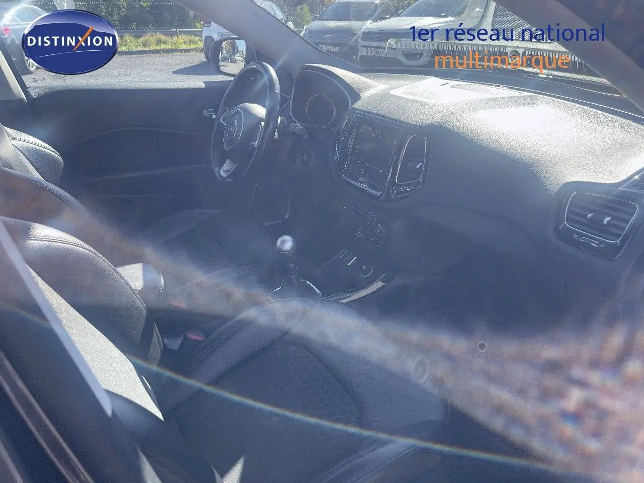 Vue intérieure côté conducteur du Jeep Compass 2019, montrant le volant, la console centrale et la boîte manuelle.