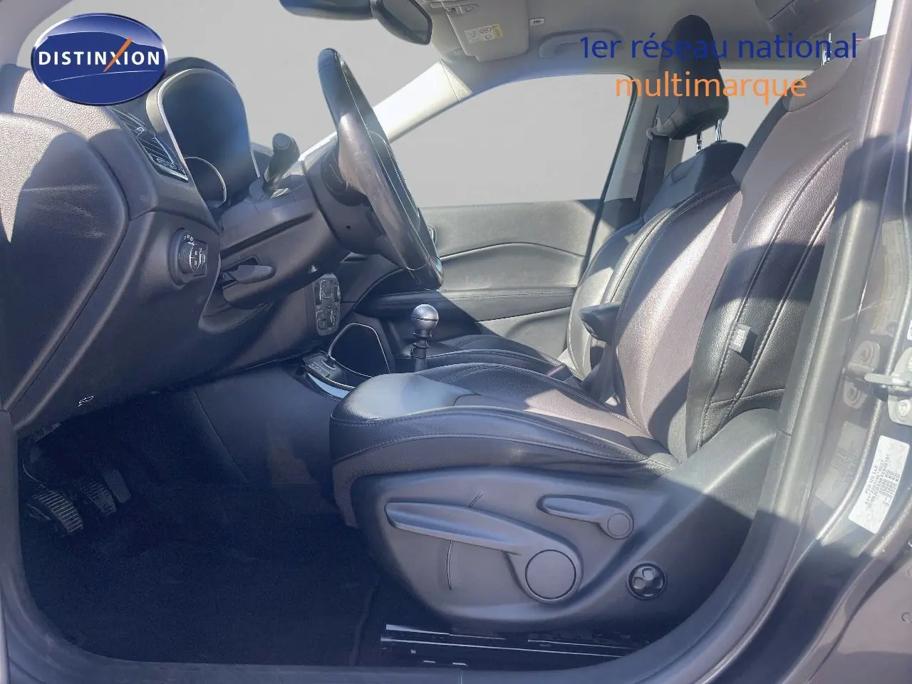 Vue intérieure côté conducteur du Jeep Compass gris foncé 2019, mettant en valeur les sièges en cuir et la boîte manuelle.