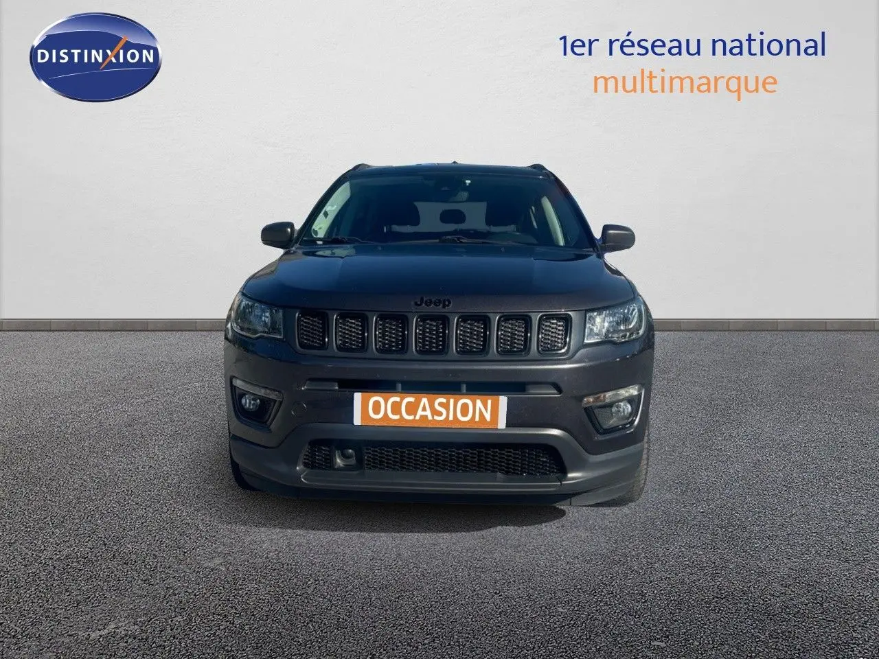 Vue avant d'un Jeep Compass gris foncé 2019 avec calandre distinctive et plaque "OCCASION" visible.