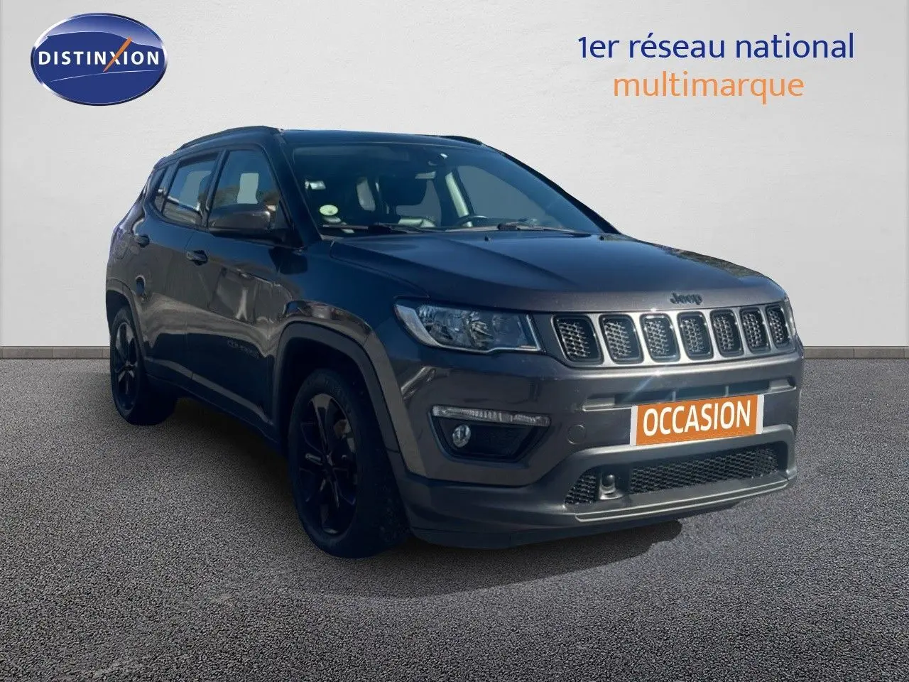 Jeep Compass gris foncé en 3/4 avant droit, version Brooklyn Edition avec jantes noires, sur fond neutre showroom.