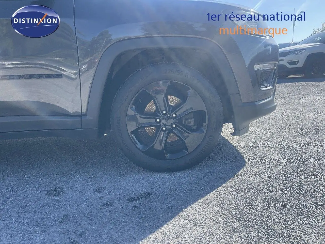 Vue latérale centrée sur la roue avant droite d'un Jeep Compass gris foncé avec jante noire brillante.