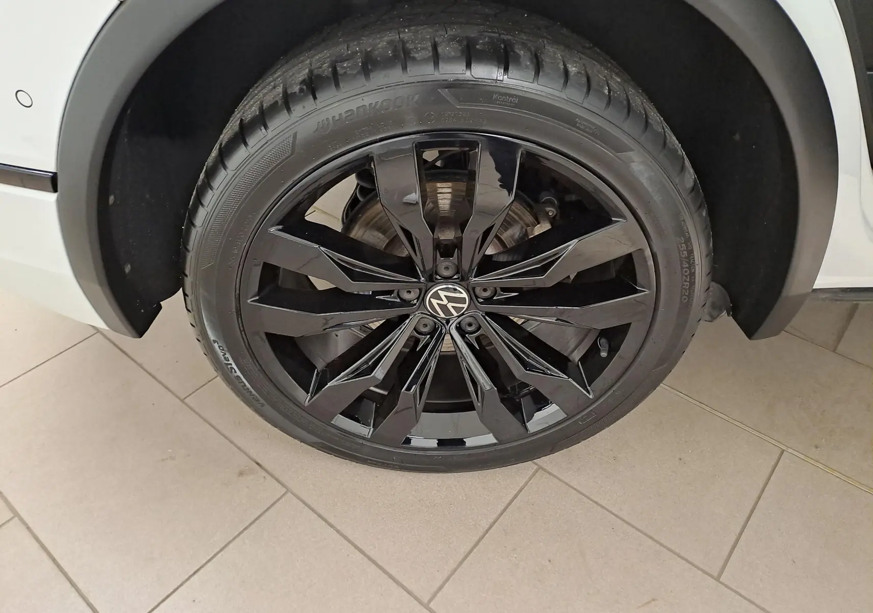 Gros plan sur la roue avant droite du Volkswagen Tiguan blanc nacré avec jante alliage noir 20 pouces Suzuka.