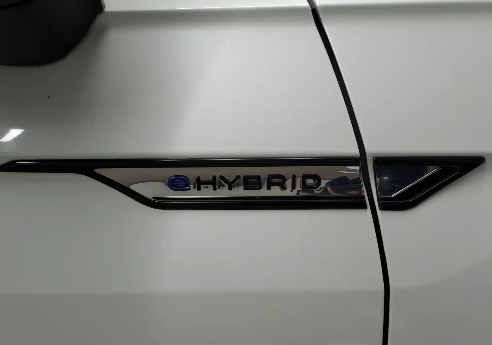 Détail du badge eHybrid sur la portière blanche nacrée d'un Volkswagen Tiguan 2023, version hybride rechargeable.