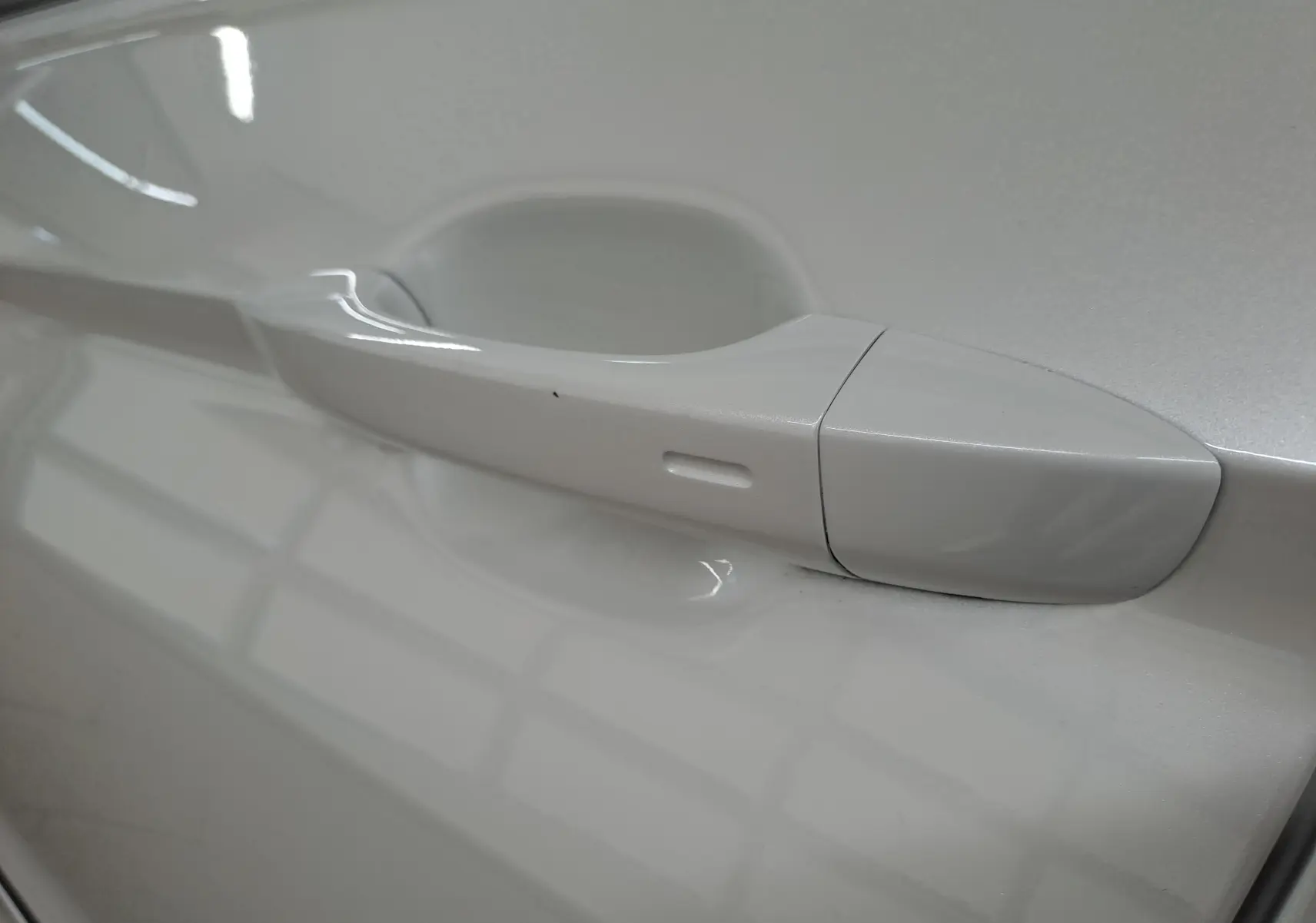 Poignée de porte côté gauche du Volkswagen Tiguan 1.4 eHybrid blanc nacré, vue rapprochée sur la finition lisse.