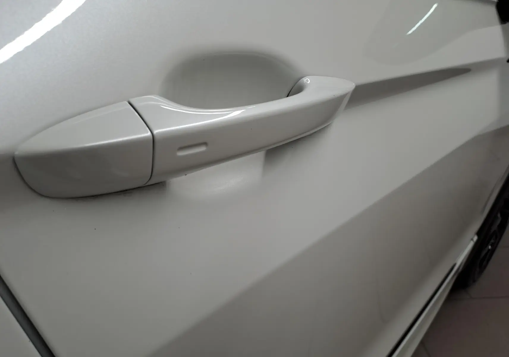 Poignée de porte côté gauche en gros plan sur Volkswagen Tiguan blanc nacré 2023 avec peinture nacrée Oryx.