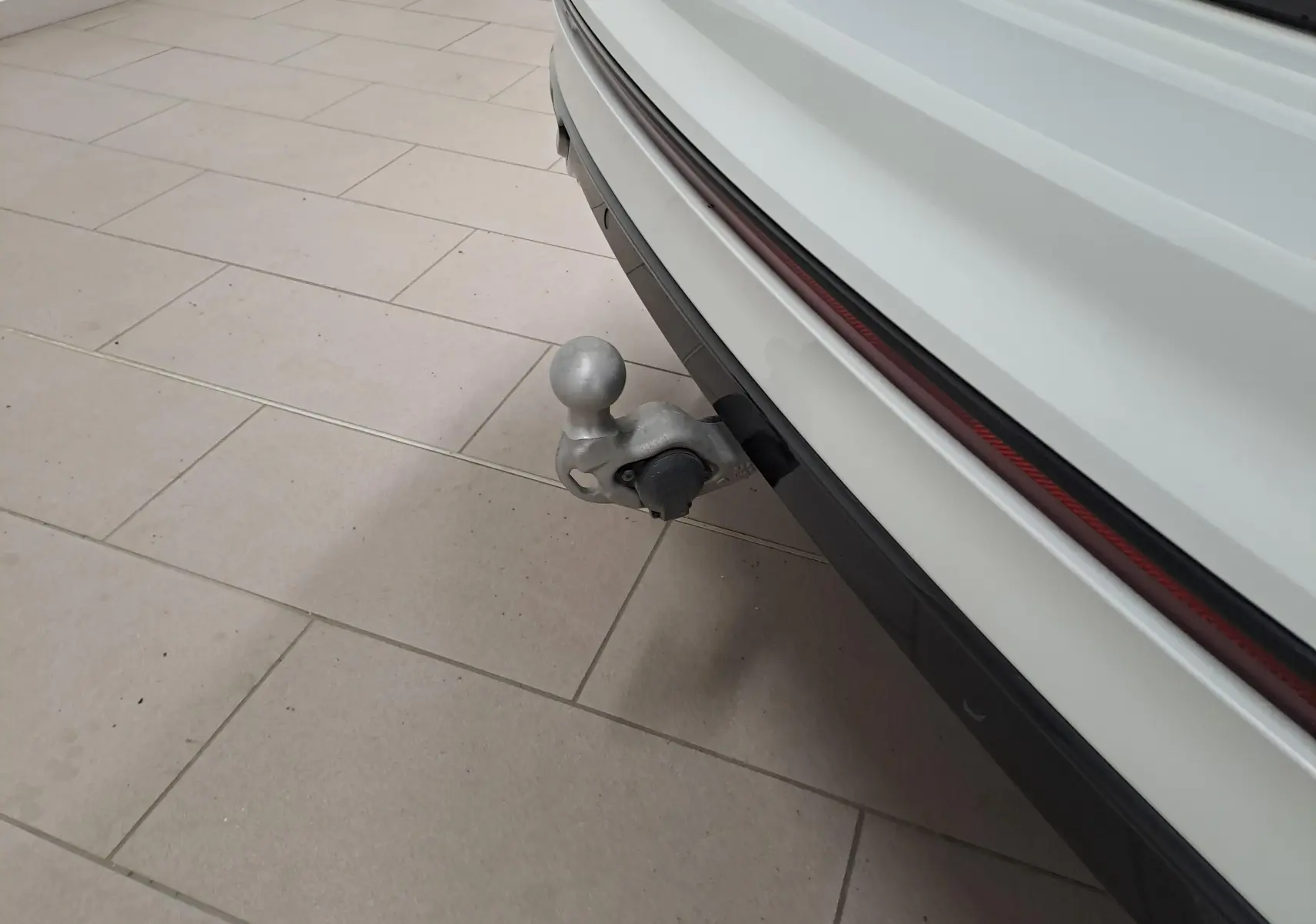 Gros plan sur le crochet d'attelage escamotable arrière d'un Volkswagen Tiguan blanc nacré, version 2023.