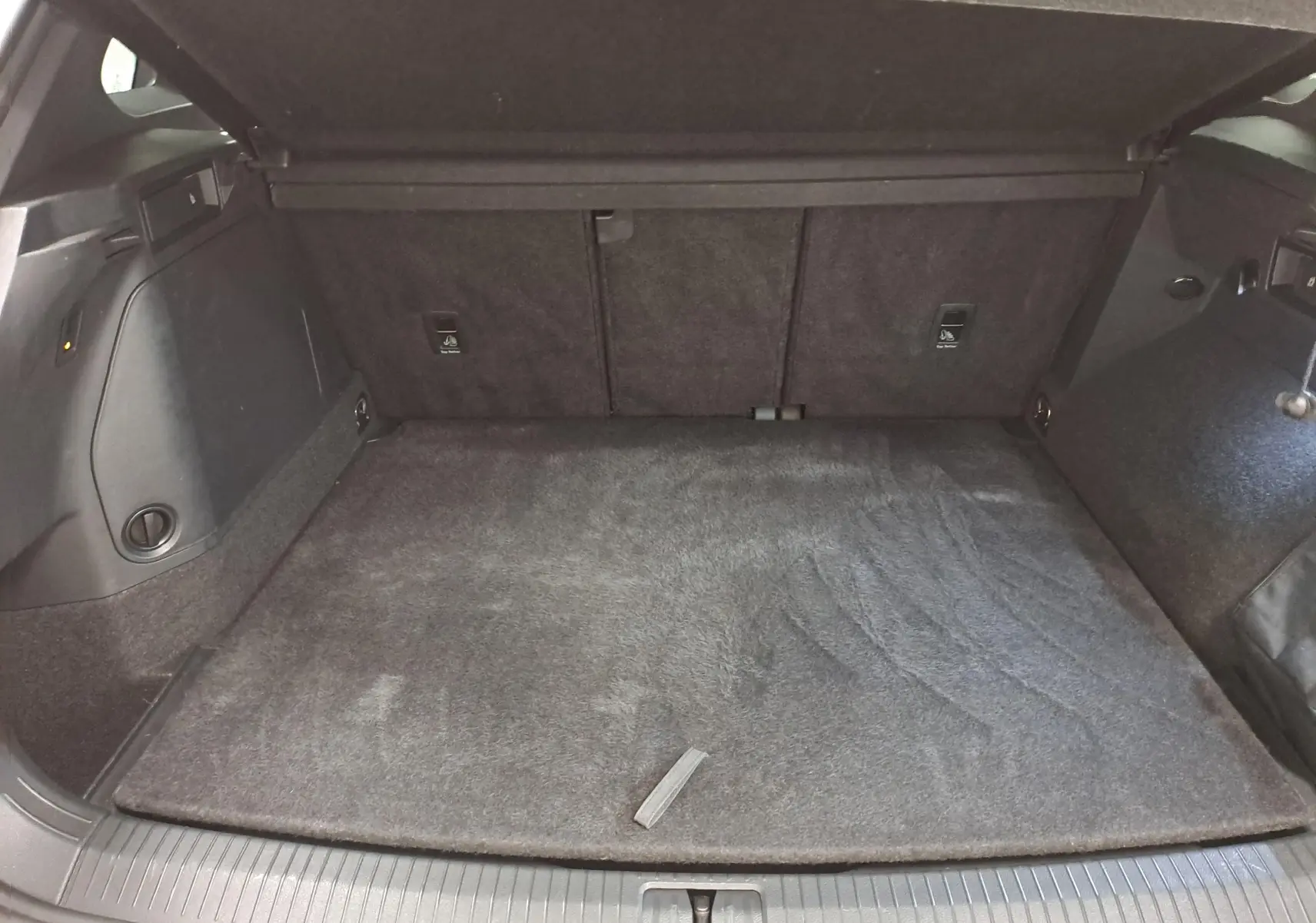 Coffre ouvert du Volkswagen Tiguan 1.4 eHybrid 2023, vue intérieure, tapis de sol gris et garnitures noires.