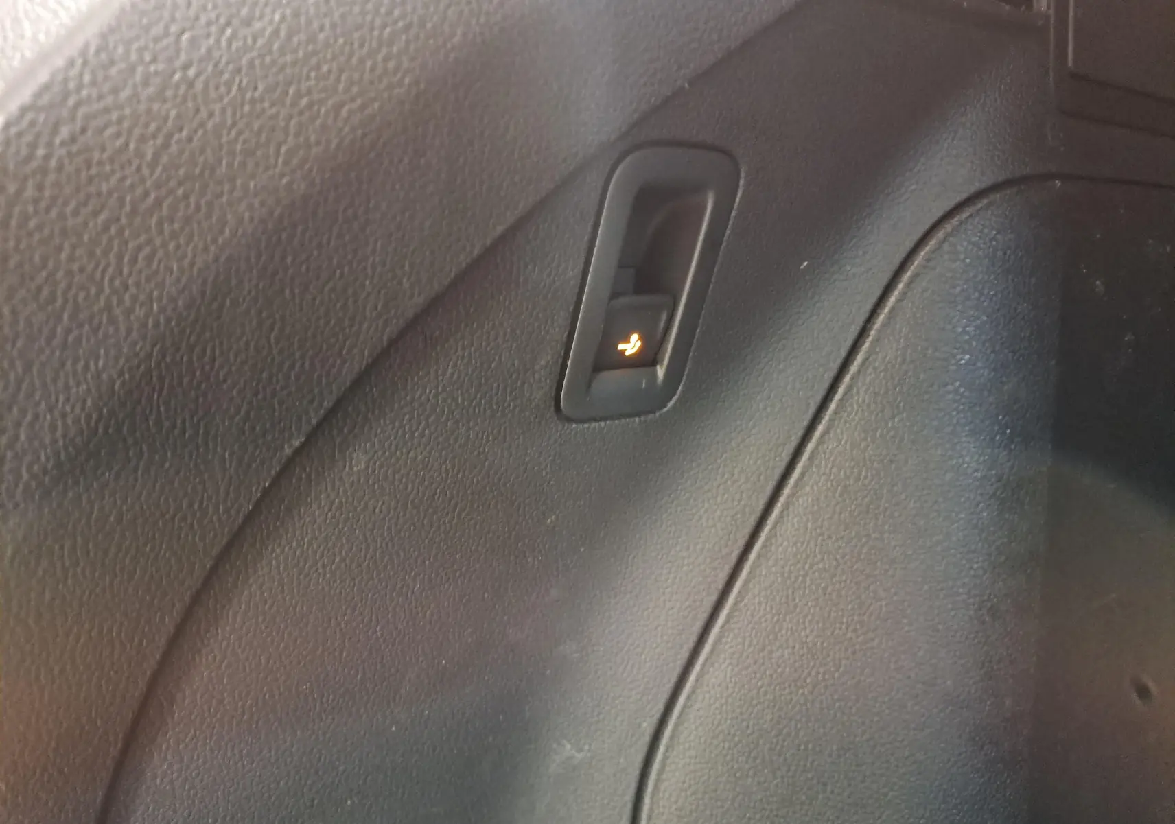 Gros plan sur le bouton de rabattement électrique des sièges dans l'habitacle noir du Volkswagen Tiguan 2023.