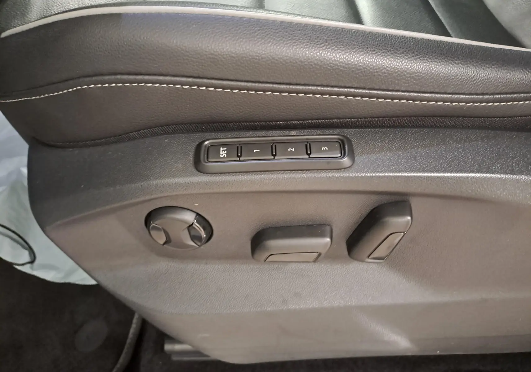 Détail des commandes de réglage électrique du siège conducteur noir du Volkswagen Tiguan blanc nacré 2023.