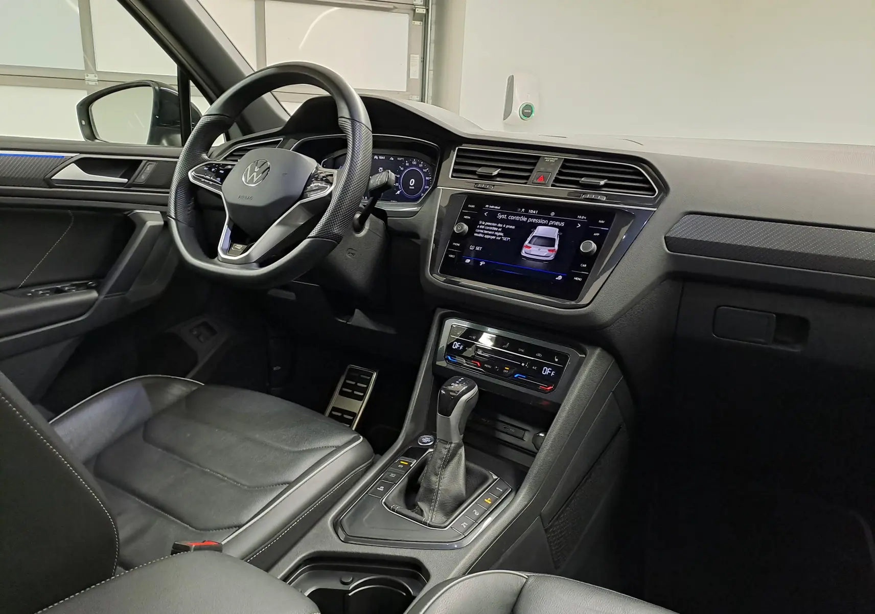 Vue intérieure côté conducteur du Volkswagen Tiguan 2023, tableau de bord et console centrale avec écran tactile et levier de vitesse.