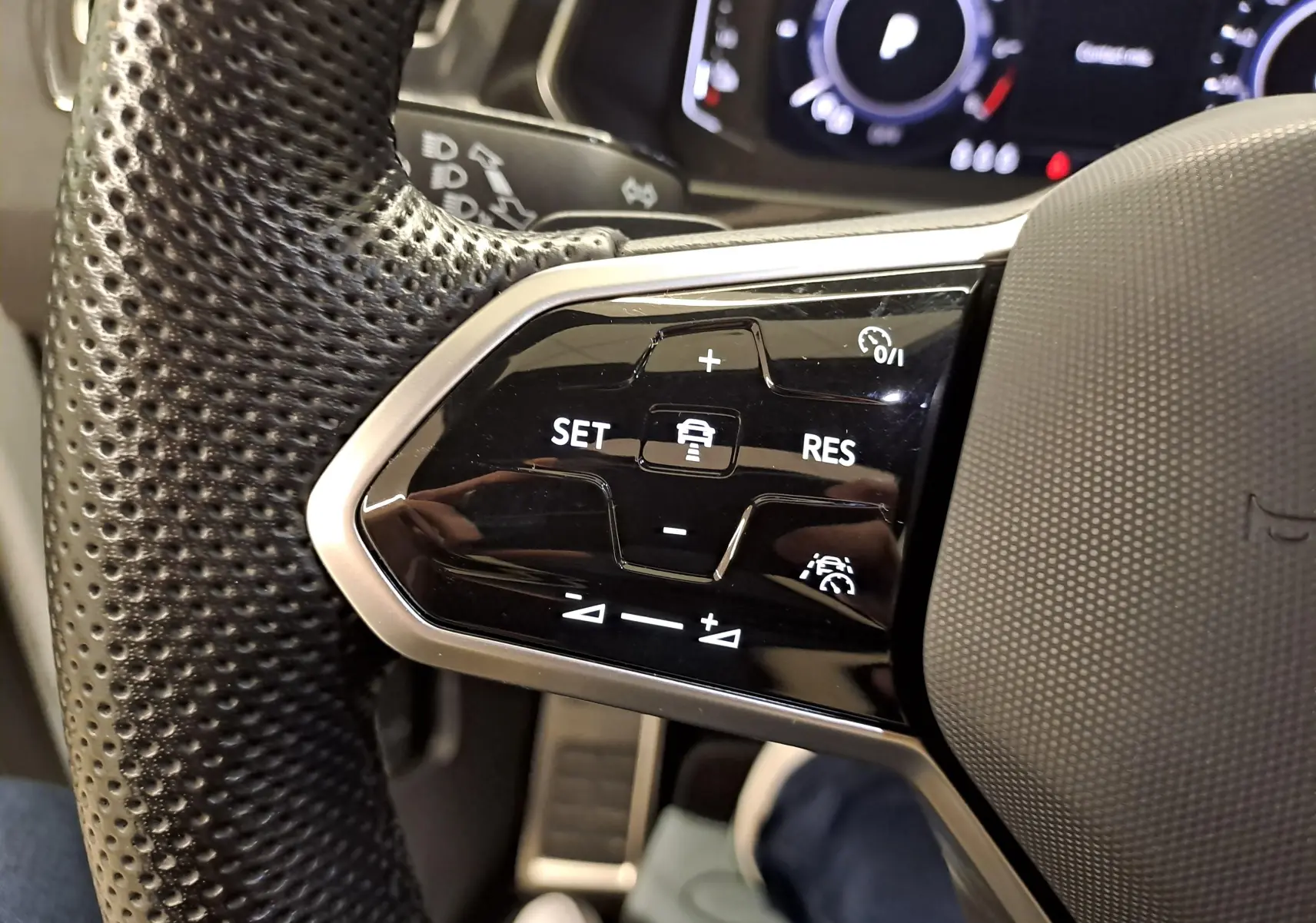 Gros plan sur les commandes du volant à gauche du Volkswagen Tiguan 1.4 eHybrid 2023, cuir perforé noir.