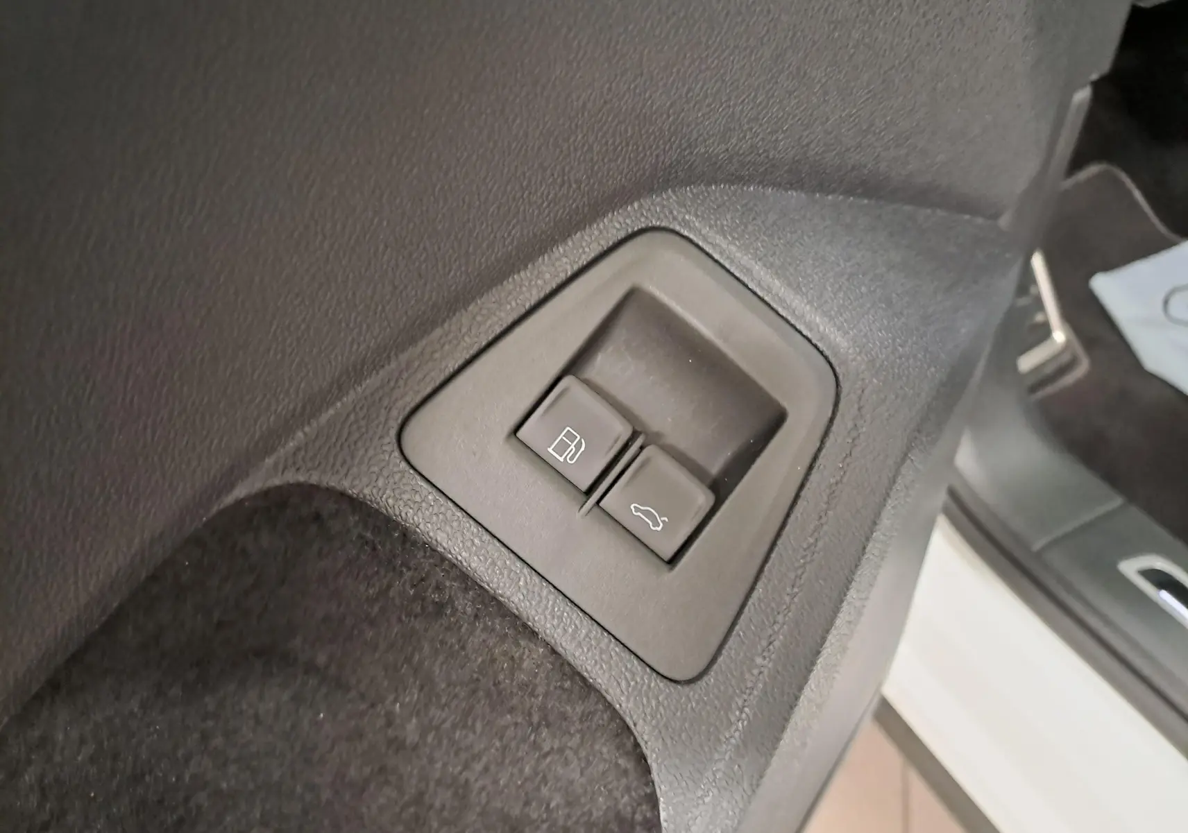 Boutons d'ouverture du coffre et de la trappe à carburant sur le côté gauche intérieur d'un Volkswagen Tiguan blanc nacré.