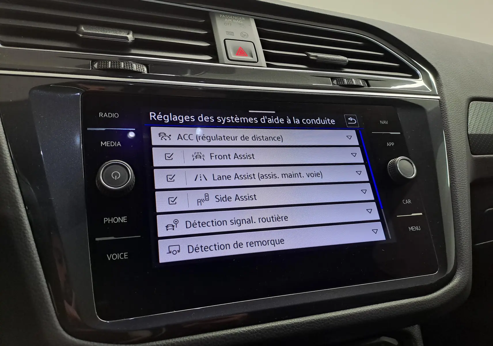 Écran tactile central du Volkswagen Tiguan 2023 affichant les réglages des aides à la conduite dans l'habitacle noir.