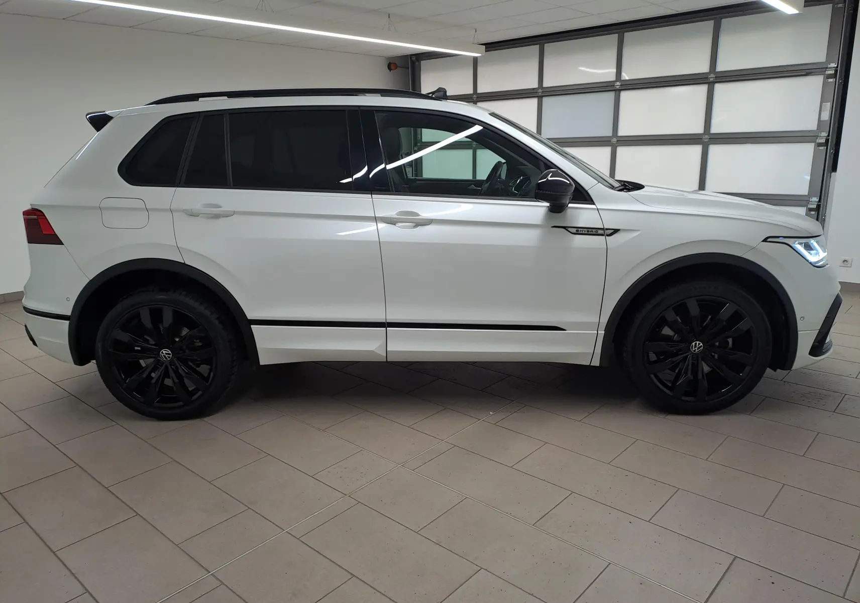 Vue de profil côté gauche du Volkswagen Tiguan 1.4 eHybrid blanc nacré avec jantes noires 20 pouces et vitres teintées.