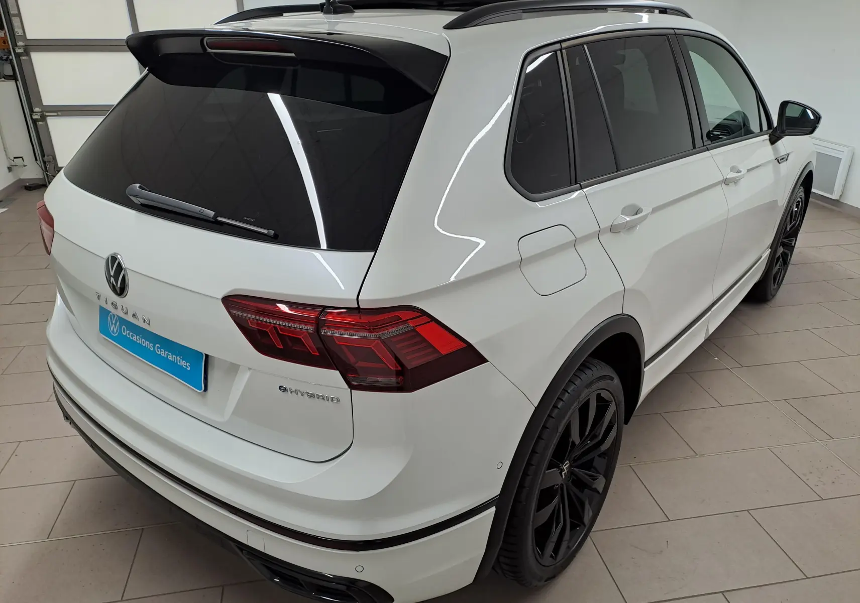 Volkswagen Tiguan blanc nacré en 3/4 arrière droit, avec jantes noires 20 pouces et vitres teintées.