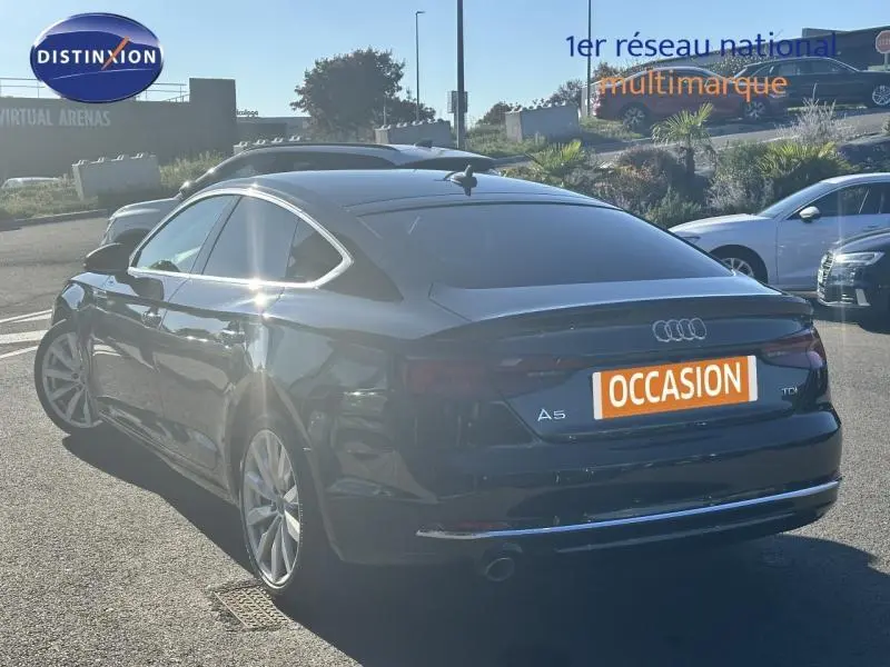 Audi A5 Sportback diesel noire vue 3/4 arrière droit, avec jantes alu et feu arrière LED distinctifs.