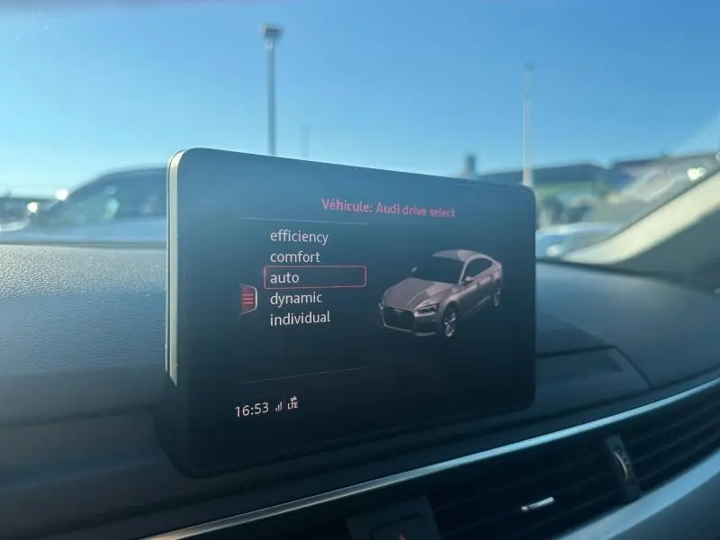 Écran central intérieur montrant le menu Audi drive select avec illustration d’une Audi A5 Sportback grise.